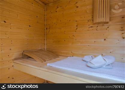 A healthy wooden hot sauna with sauna accessories and wooden bucket. A healthy wooden hot sauna with sauna accessories