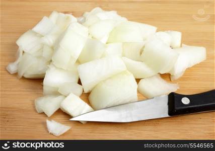 A heap of diced onion on a chopping board with a knife