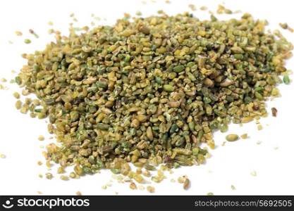 A heap of frikeh or freekeh grains on a white background. The cereal is made from immature, green wheat which is fire-roasted to make a healthy, low-glycemic-index food which is high in protein and minerals, making it an option for a diabetic diet. Boiled freekeh is a common Middle Eastern food.