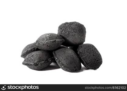 A heap of several charcoal bricks stacked on to a white background.