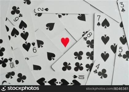 A heart in the middle of black suits of playing cards