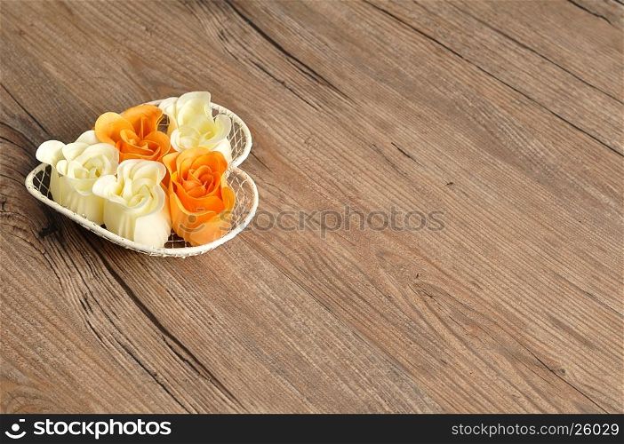 A heart shape wire basket filled with orange and white rose shape soaps