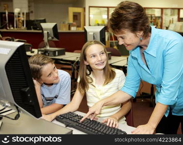 A helpful teacher showing school kids how to use the computer.