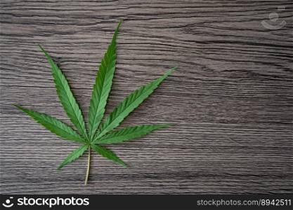 A hemp leaf on a wooden texture background.
