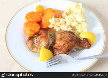 A high angle view of chicken thighs, marinaded in lemon juice and herbs and then roasted, served with mashed boiled potatoes and boiled carrots