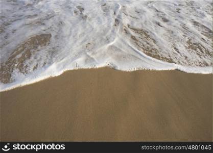 A high angle view of foamy sea water pushing out on to the beach.