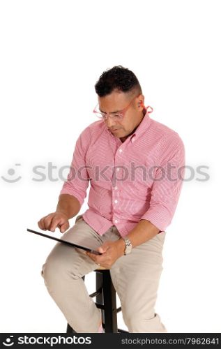 A Hispanic man sitting on a chair with safety glasses and earplug&rsquo;s workingwith his tablet computer, isolated for white background.