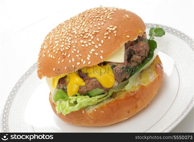 A homemade beefburger patty in a sesame seed bun, with lettuce, arugula (rocket), mustard and a slice of cheese