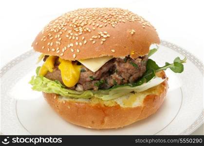 A homemade beefburger patty in a sesame seed bun, with lettuce, arugula (rocket), mustard and a slice of cheese