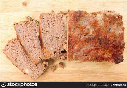 A homemade meatloaf, sliced, on a chopping board seen from above,