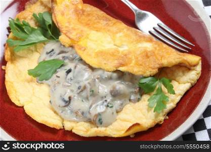 A homemade souffle omelet served with mushrooms in a creamy sauce, garnished with flat-leaf parsley, high angle view