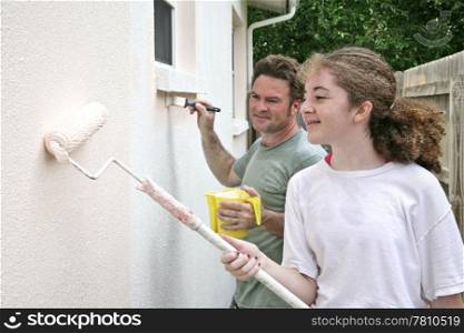 A horizontal view of a father and daughter painting their house together.