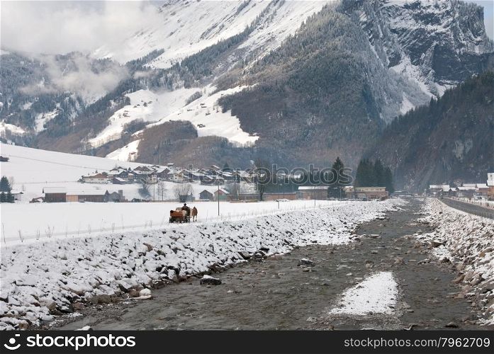 A horse-drawn sleigh, on a path adjacent to a fast-flowing river, Austria