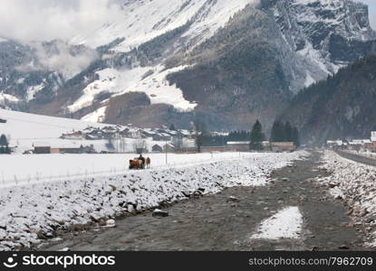 A horse-drawn sleigh, on a path adjacent to a fast-flowing river, Austria