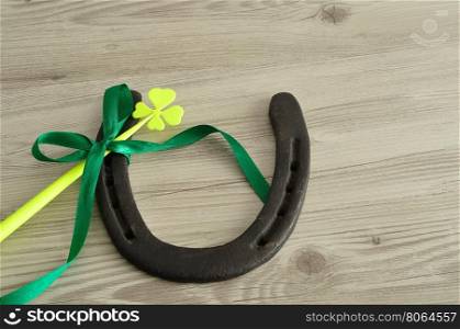 A horseshoe displayed with a four leaf clover and a green bow for St. Patrick's day