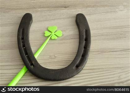 A horseshoe displayed with a four leaf clover for St. Patrick's day