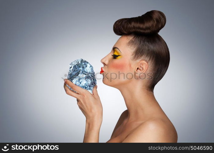 A hot photo of beauty touching her face with the piece of ice holding in her hands.