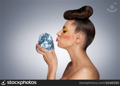 A hot photo of beauty touching her face with the piece of ice holding in her hands.