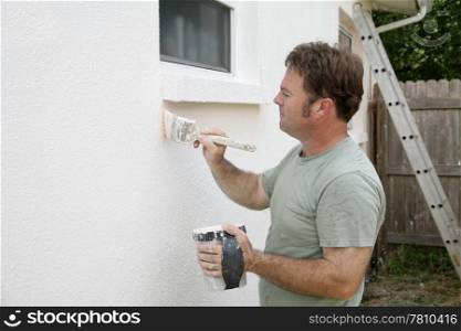 A house painter edging around a window with a brush. Room for text.