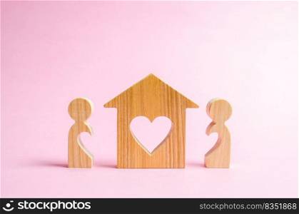 A house with a heart stands between a pair of lovers. The concept of finding a love nest. Affordable housing for young families and couples. Mortgage, purchase credit. Valentine’s Day.