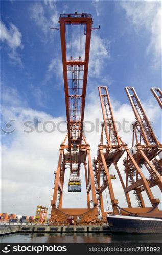 A huge cargo crane, carrying a container in an industrial harbor environment