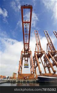A huge cargo crane, carrying a container in an industrial harbor environment