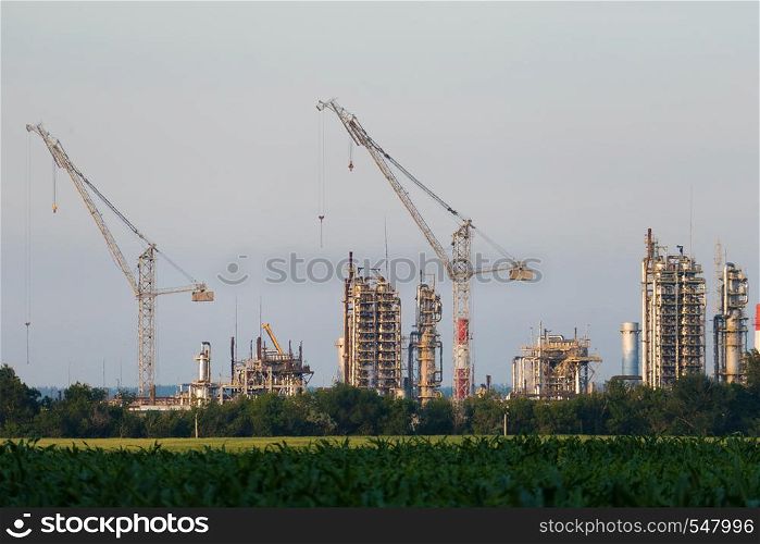 A huge oil refinery with cranes under construction.. A huge oil refinery with cranes under construction