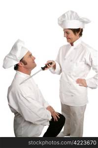 A humorous photo of a new chef being knighted by his cooking school instructor. Isolated on white.