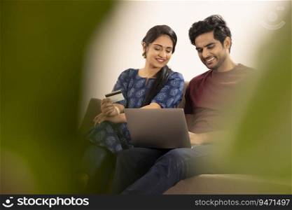 A HUSBAND AND WIFE SITTING TOGETHER AND DOING ONLINE TRANSACTION