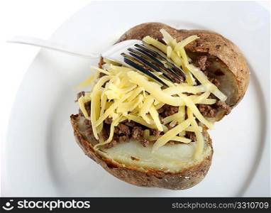 A jacket or baked potato topped with minced beef and cheese, with a fork on a white plate