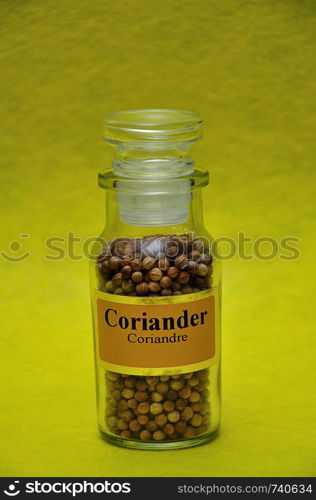 A jar filled with Coriander on a yellow background