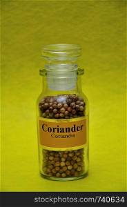 A jar filled with Coriander on a yellow background