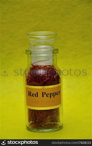 A jar filled with red pepper on a yellow background