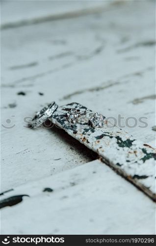 A jewelry concept super close up shot of a diamond ring over a wooden plank with metal and light colors