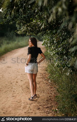 A joyful beauty walks in the rays of the setting sun in nature.. A young beauty walks under the rays of the summer sun in the meadows