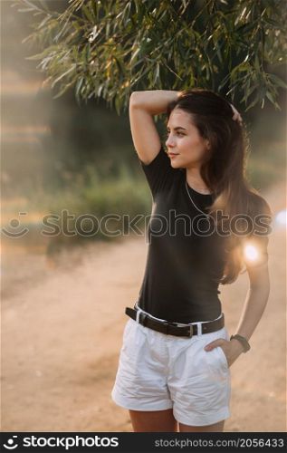A joyful beauty walks in the rays of the setting sun in nature.. A young beauty walks under the rays of the summer sun in the meadows