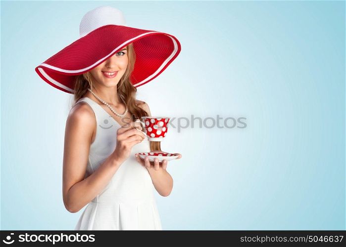A joyful photo of girl in vintage wide-brimmed hat holding a cup.