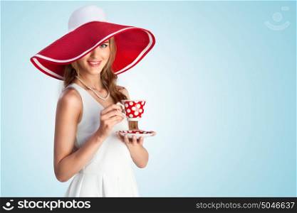 A joyful photo of girl in vintage wide-brimmed hat holding a cup.
