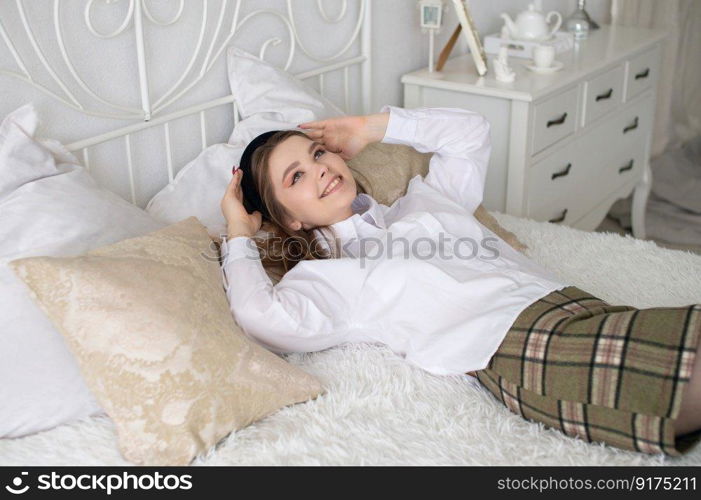 A joyful student girl is lying on the bed looking up laughing. A joyful student girl lies on the bed and laughs