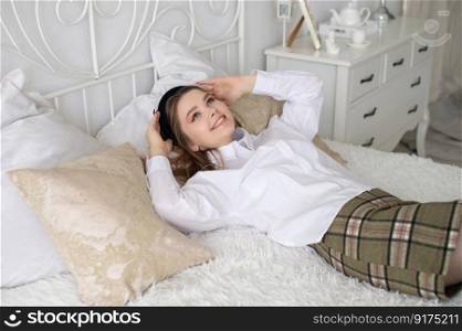 A joyful student girl is lying on the bed looking up laughing. A joyful student girl lies on the bed and laughs