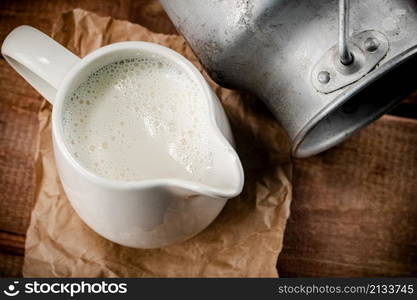 A jug of fresh milk on the table. On a wooden background. High quality photo. A jug of fresh milk on the table.