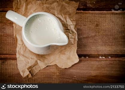 A jug of fresh milk on the table. On a wooden background. High quality photo. A jug of fresh milk on the table.