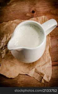 A jug of fresh milk on the table. On a wooden background. High quality photo. A jug of fresh milk on the table.