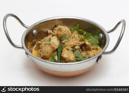 A kadai serving bowl of balti chicken pasanda curry, garnished with coriander leaves and a green chilli. This curry is made with yoghurt , cream and chopped coriander as well as the usual spices, to give a fairly mild and creamy flavour.