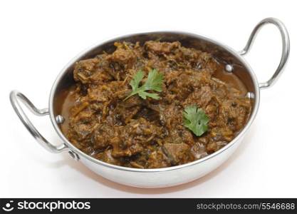 A kadai serving bowl of methi gosht, or lamb curried with fresh fenugreek leaves, a north Indian speciality,garnished with a coriander leaf.