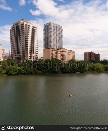 A Kayaker moves along the Colorado River dwarfed by the Austin Skyline