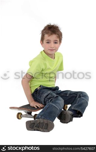 A kid sitting on his skateboard.