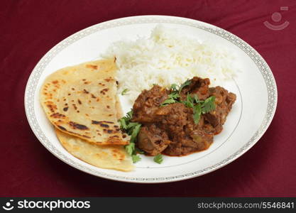 A kidney masala bhuna-type curry served with rice and paratha bread, garnished with coriander leaves