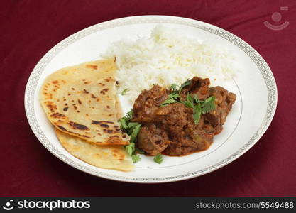 A kidney masala bhuna-type curry served with rice and paratha bread, garnished with coriander leaves