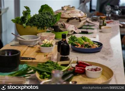 A kitchen with a cooking table in the middle of the room and the table is full of ingredients for cooking. The concept of a food healthy lifestyle. No focus, specifically.